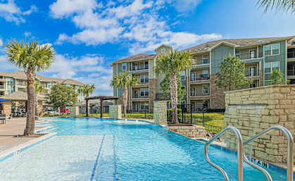 a swimming pool with palm trees in front of an apartment building