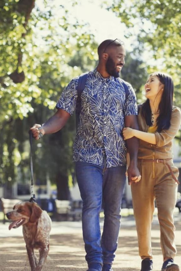 a man and woman walking their dog in a park