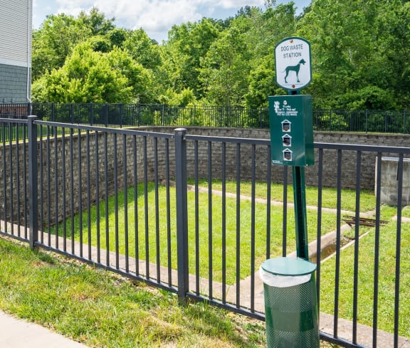 a black wrought iron fence with a green sign on it and a yard behind it