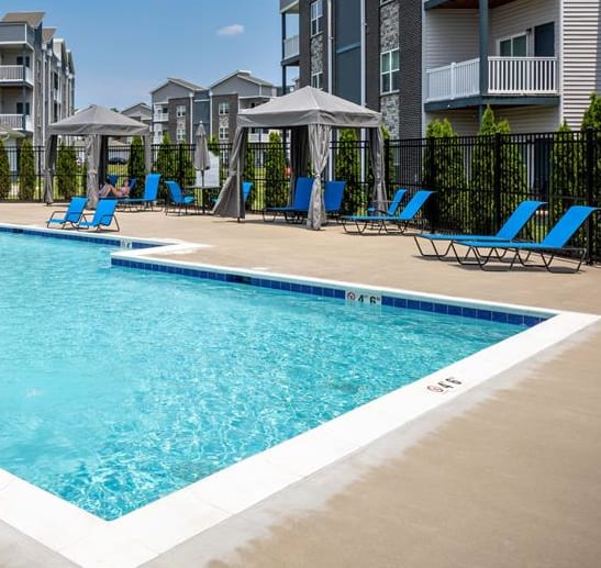 a resort style pool with blue chairs and a building in the background