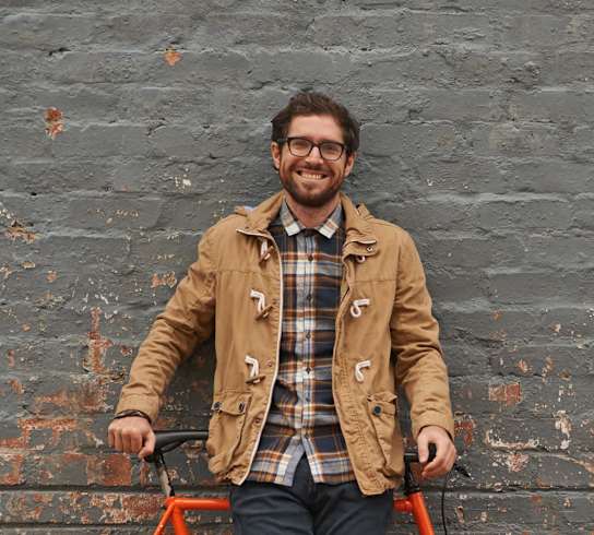 a man standing in front of a orange bikeat First Street Lofts in Downtown Bismarck, Bismarck, ND