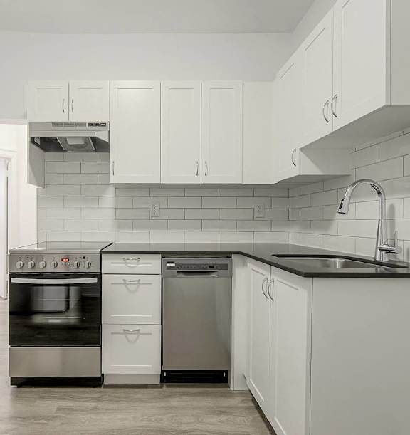 the living room and kitchen of an apartment with wood floors and white cabinets at 723 Bloor Apartments, Canada