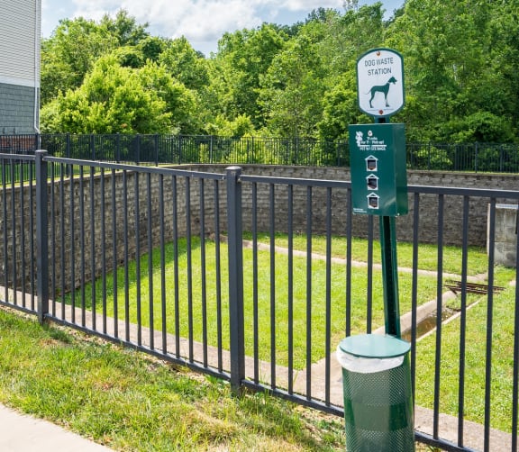 a black wrought iron fence with a green sign on it and a yard behind it