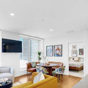 A living room with a yellow couch and a flat screen TV.