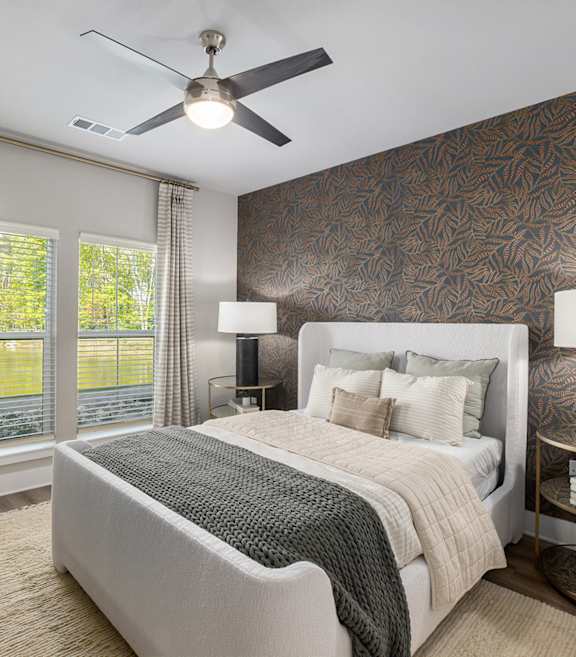 A bedroom with a large bed and a ceiling fan.