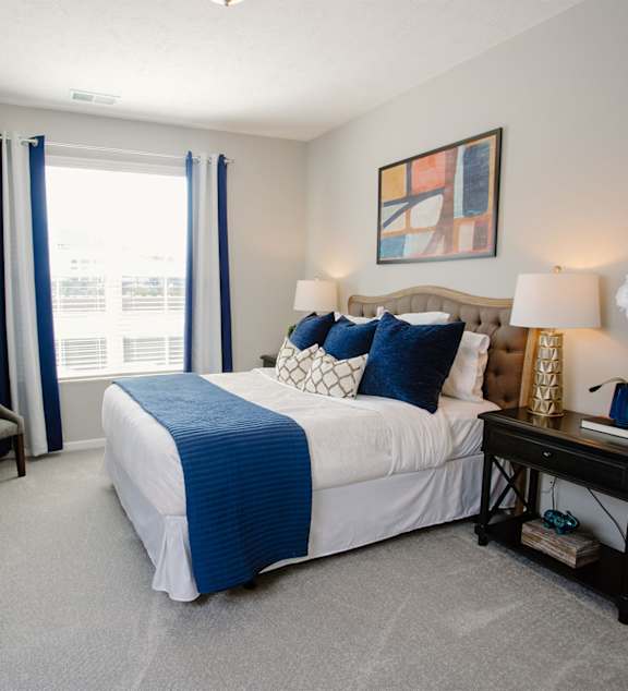 A bedroom with a bed, nightstand, and window.