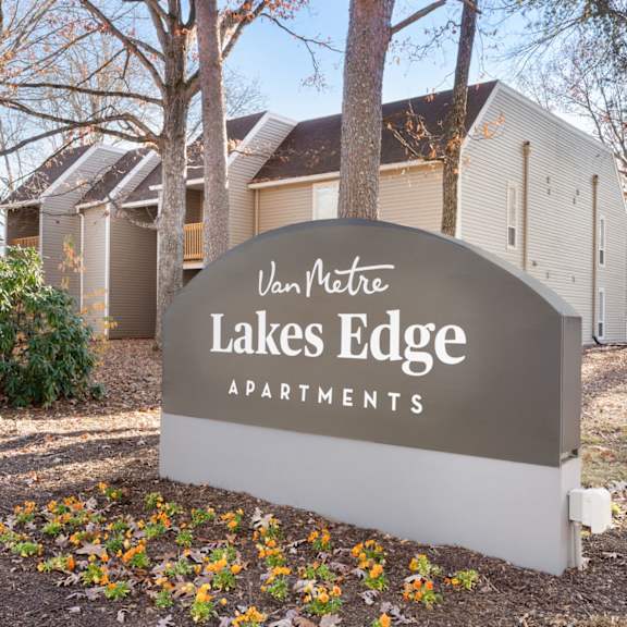 A bedroom with a bed, bench, and window. at Lakes Edge Apartments, North Carolina