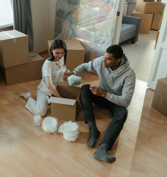 a couple sitting on the floor surrounded by boxes