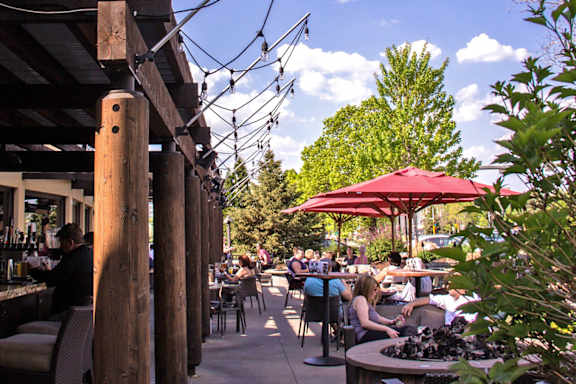 Restaurant with people sitting at tables under umbrellas at The Bosk Apartment Homes, Woodbury, MN, 55125