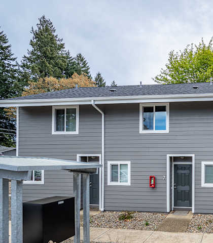 A grey house with a red fire extinguisher on the wall.