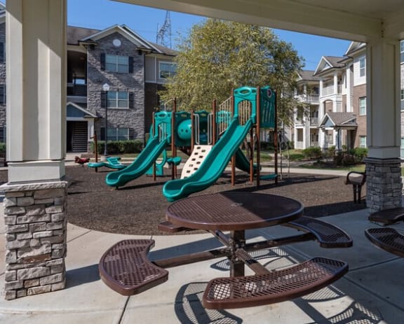 Covered patio with tables and chairs and playground equipment