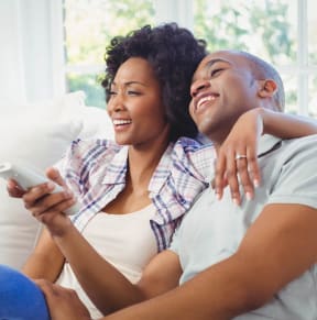 Man and Woman Sitting on Sofa Together Smiling