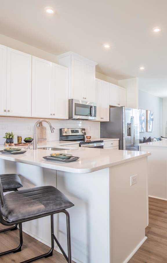 A kitchen with white cabinets and a black chair.