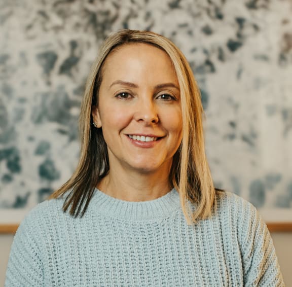 a woman in a blue sweater smiling at the camera