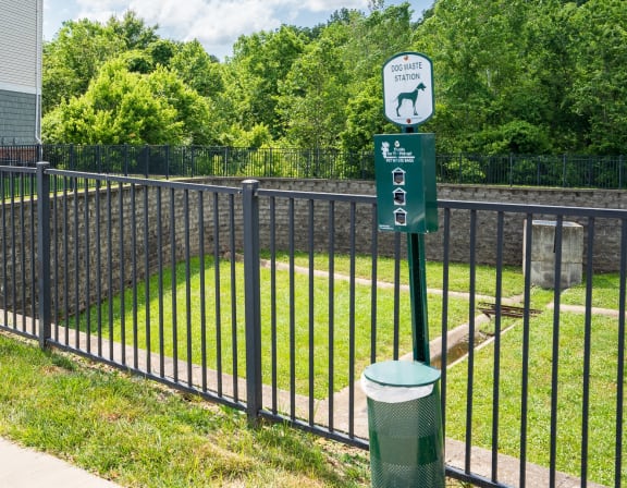 a black wrought iron fence with a green sign on it and a yard behind it