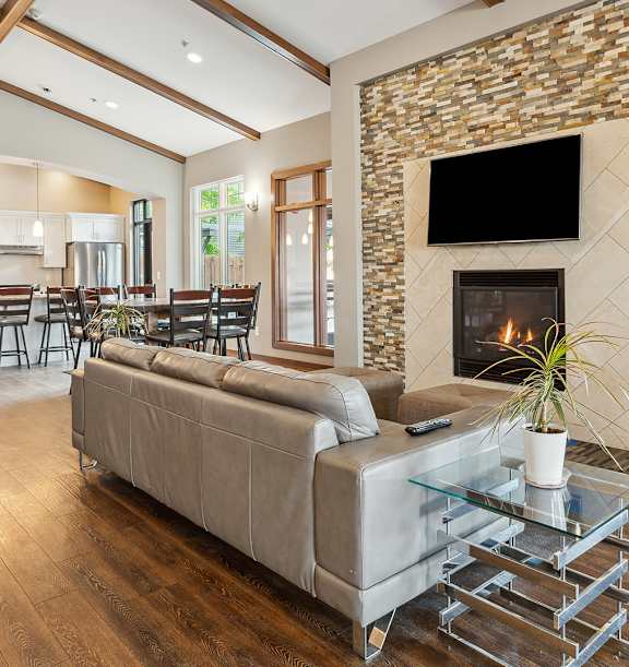 A modern living room with a stone fireplace and a glass coffee table.