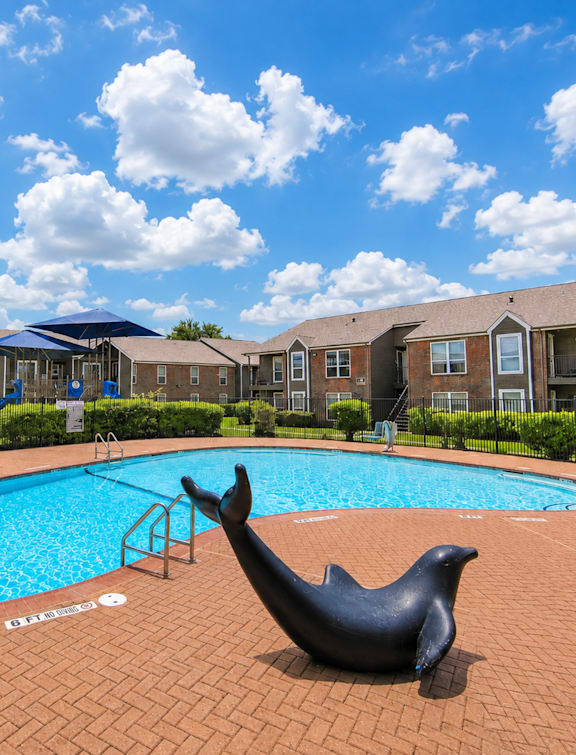 A pool with a seal statue in front of apartment buildings.