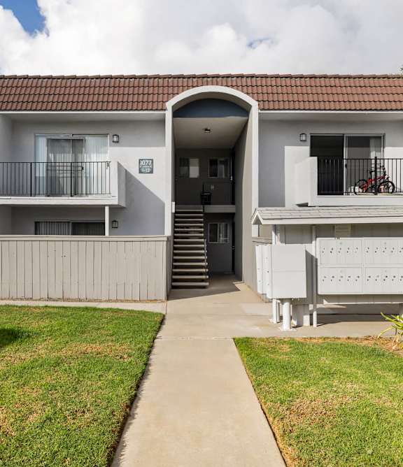 A row of white houses with a concrete pathway in the middle.
