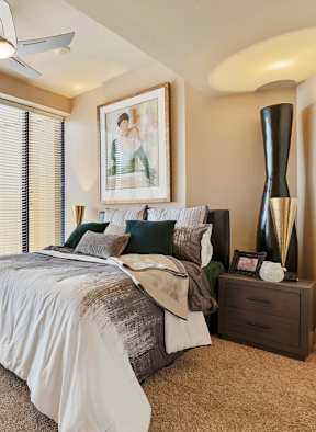 A bedroom with a bed, nightstand, and a ceiling fan.