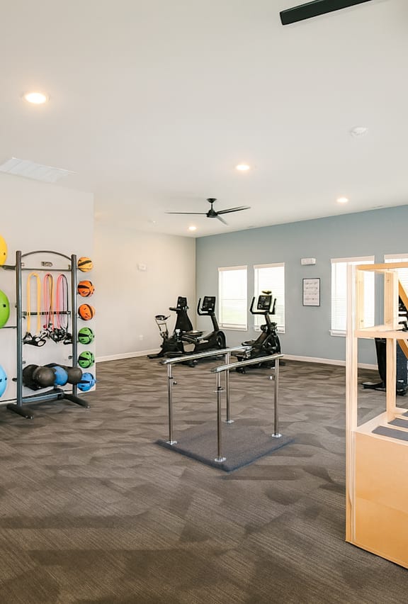 A room with a variety of exercise equipment including a treadmill, stationary bike, and a rowing machine.