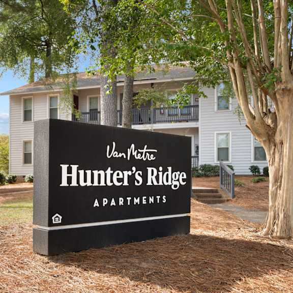 A bedroom with a bed, bench, and window. at Hunter's Ridge Apartments, Fayetteville