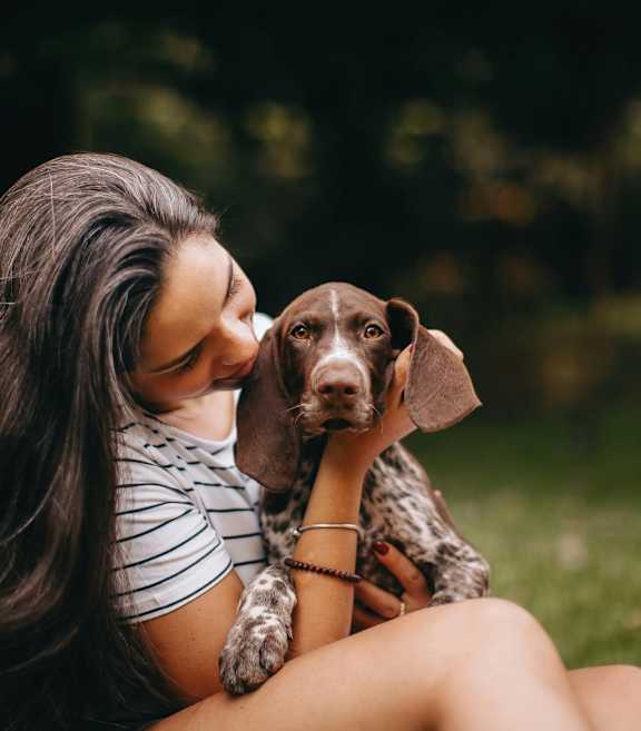 A woman is sitting on the grass with her dog.