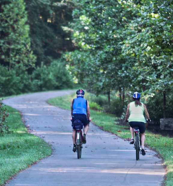 A woman riding a bike on a paved path in a park.