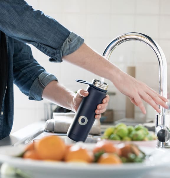 a man is washing his hands with a water filter in the kitchen