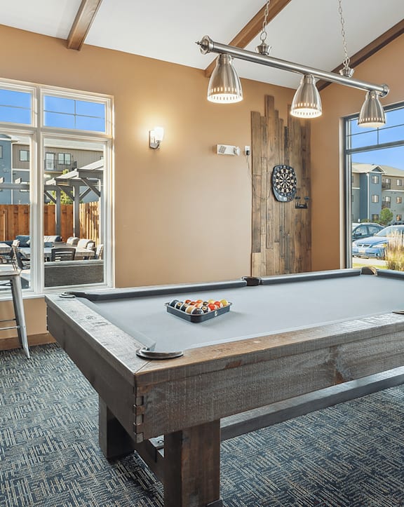 A pool table in a room with a view of the parking lot outside.