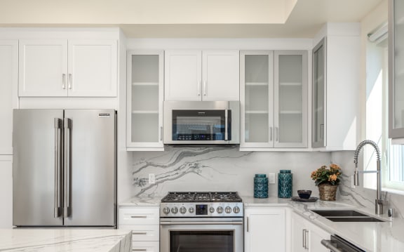 a white kitchen with stainless steel appliances and white cabinets