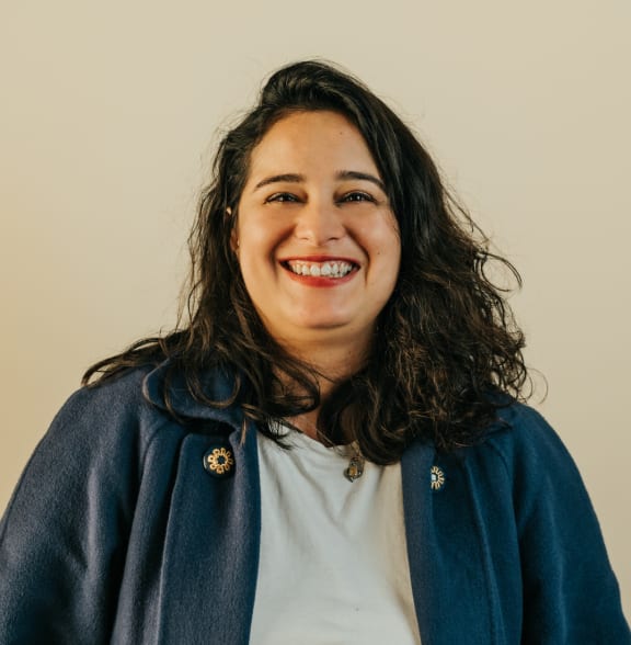 a smiling woman wearing a blue jacket and a white shirt