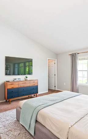 A bedroom with a bed, dresser, and window.