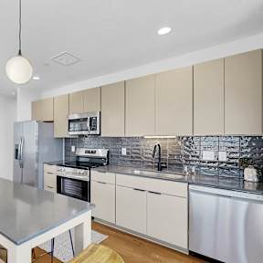 A modern kitchen with a stainless steel island and wooden flooring.