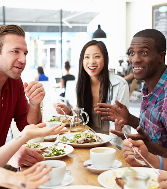 A group of people are sitting around a table eating food.