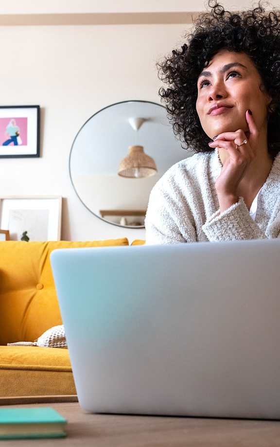 A woman with curly hair is sitting in front of a laptop.