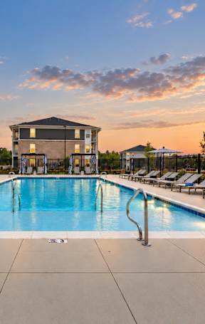 A large swimming pool surrounded by lounge chairs and umbrellas.