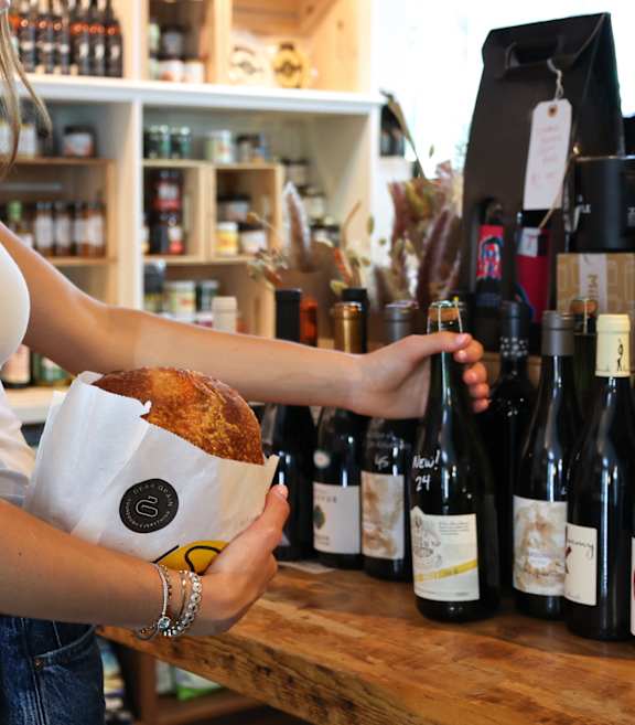 A woman is holding a bottle of wine in a store at Queen St East in Scarborough, ON