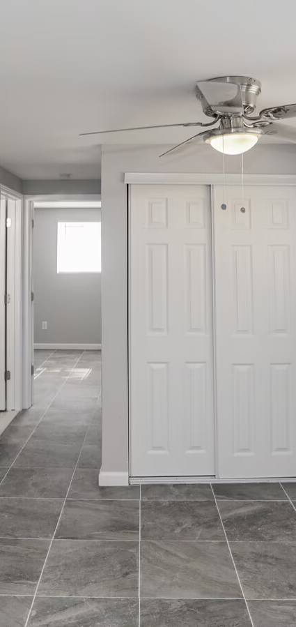 A spacious room with a ceiling fan and wooden flooring.