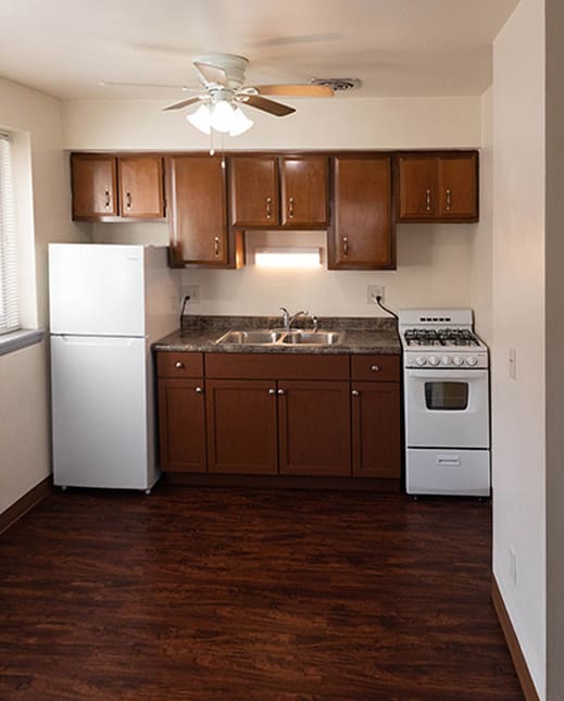 a kitchen with white appliances and wooden cabinets and a ceiling fan  at Prospect East Apartments, 53202