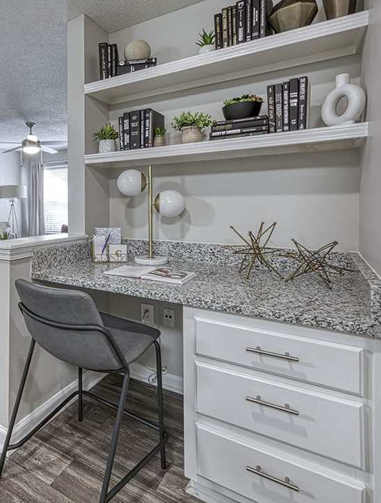 A kitchen with a desk and a chair in front of it.