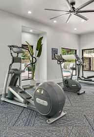 A home gym with a treadmill, weights, and exercise equipment.
