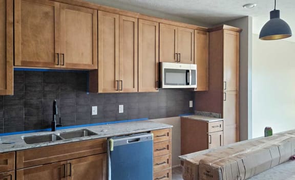 a kitchen under construction with wooden cabinets and a sink and a microwave
