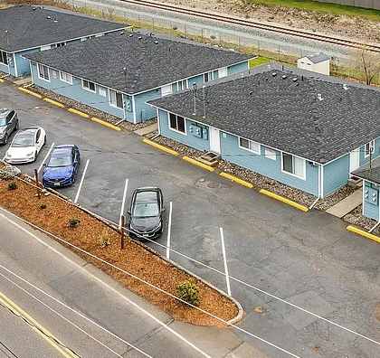 A parking lot with a few cars and a building with a yellow line in front of it.
