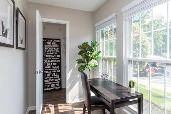 A black and white framed picture hangs on a white wall above a black table.