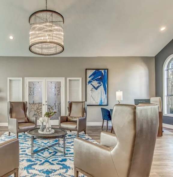 A large, modern living room with a patterned rug and a chandelier.