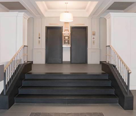 the lobby of a building with stairs and two doors