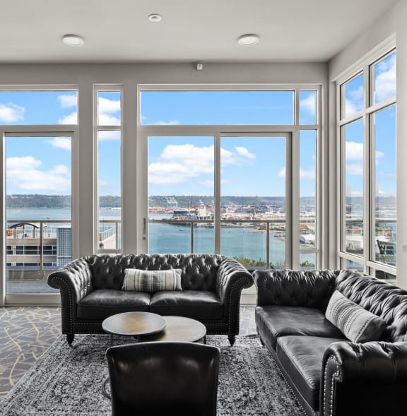 a living room with leather couches and a view of a river and a city