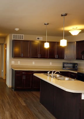 A kitchen with dark wood cabinets and a white countertop at Cedarbrooke Place , Iowa