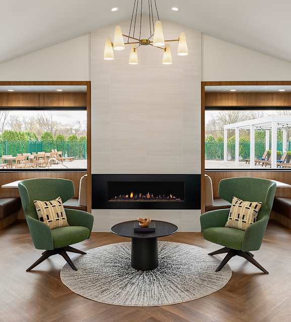 a living room with two green chairs and a fireplace