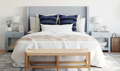 a bedroom with white walls and a bed with blue pillows
